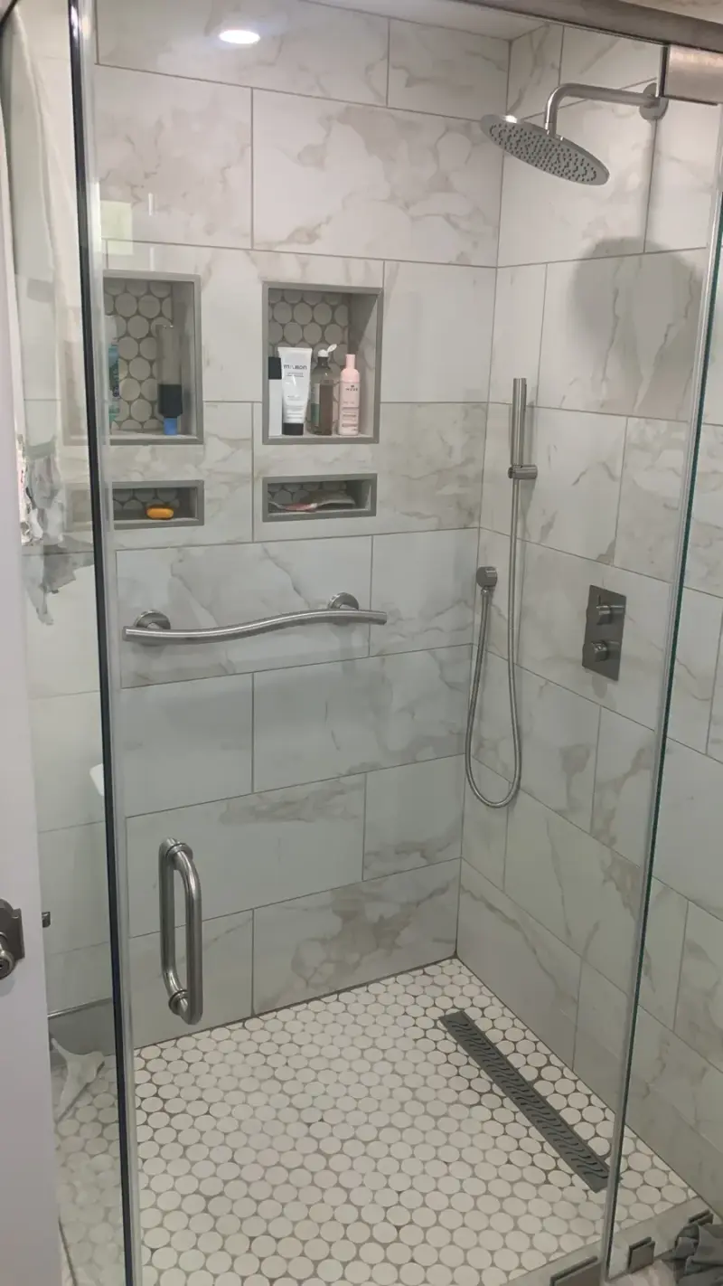Walk-in shower with marble-look tile and built-in storage niches in a Woodland Hills bathroom remodel.